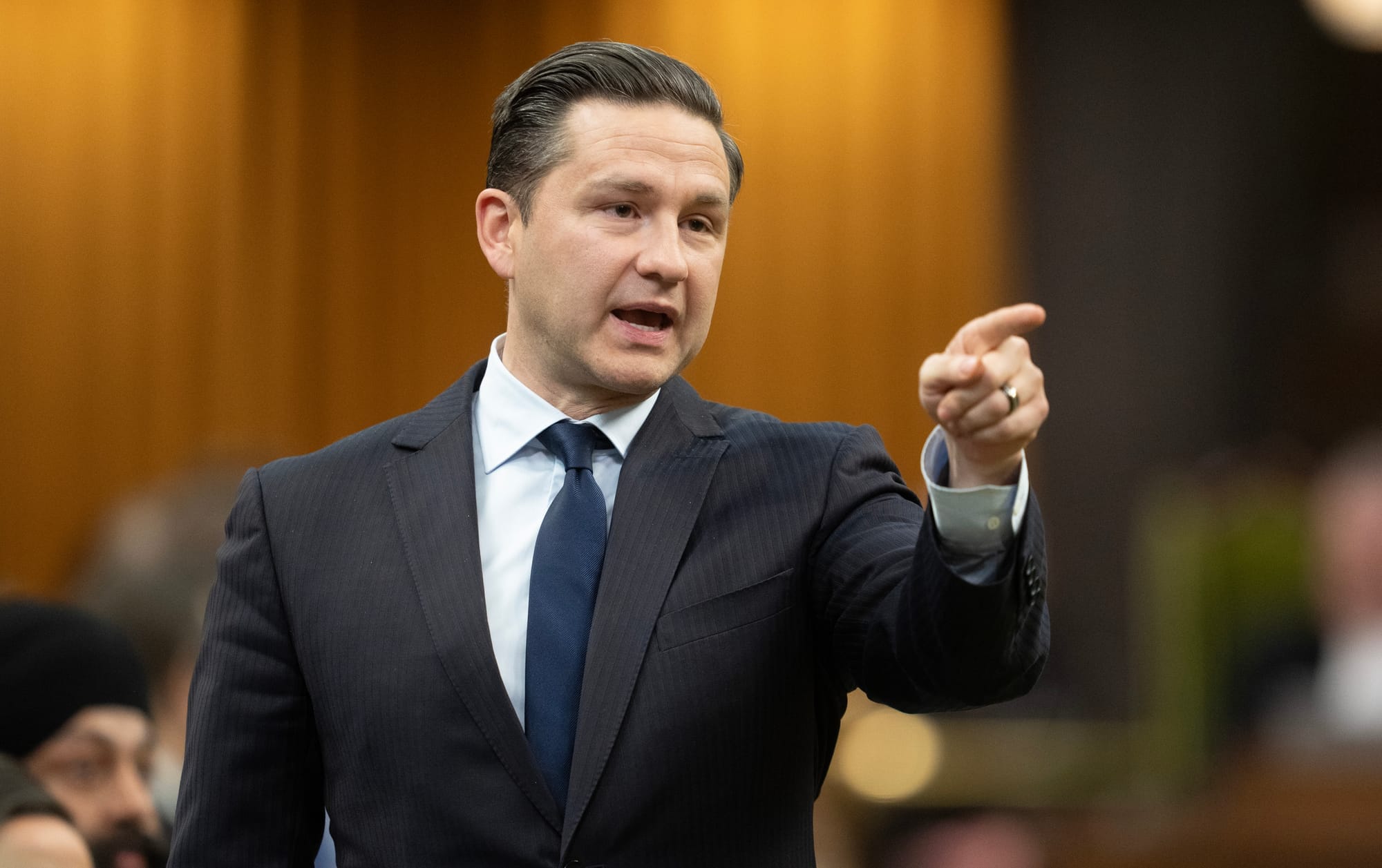 Pierre Poilievre points in the distance while standing in the House of Commons.