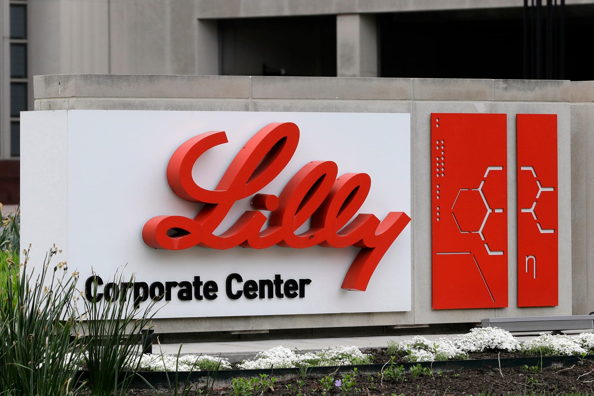 A sign with the Eli Lilly Logo is seen outside a concrete office building.