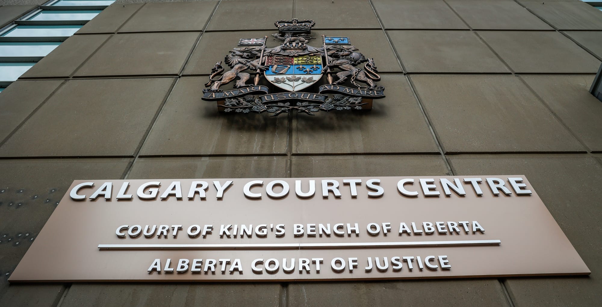 A coat of arms and a sign reading 'Calgary Courts Centre' are displayed on the side of a building.