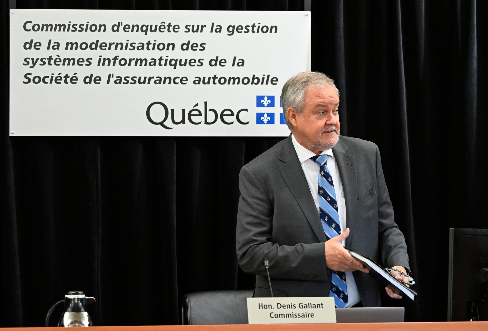 Commissioner Denis Gallant sits down at a long desk for an inquiry into Quebec IT contracts 
