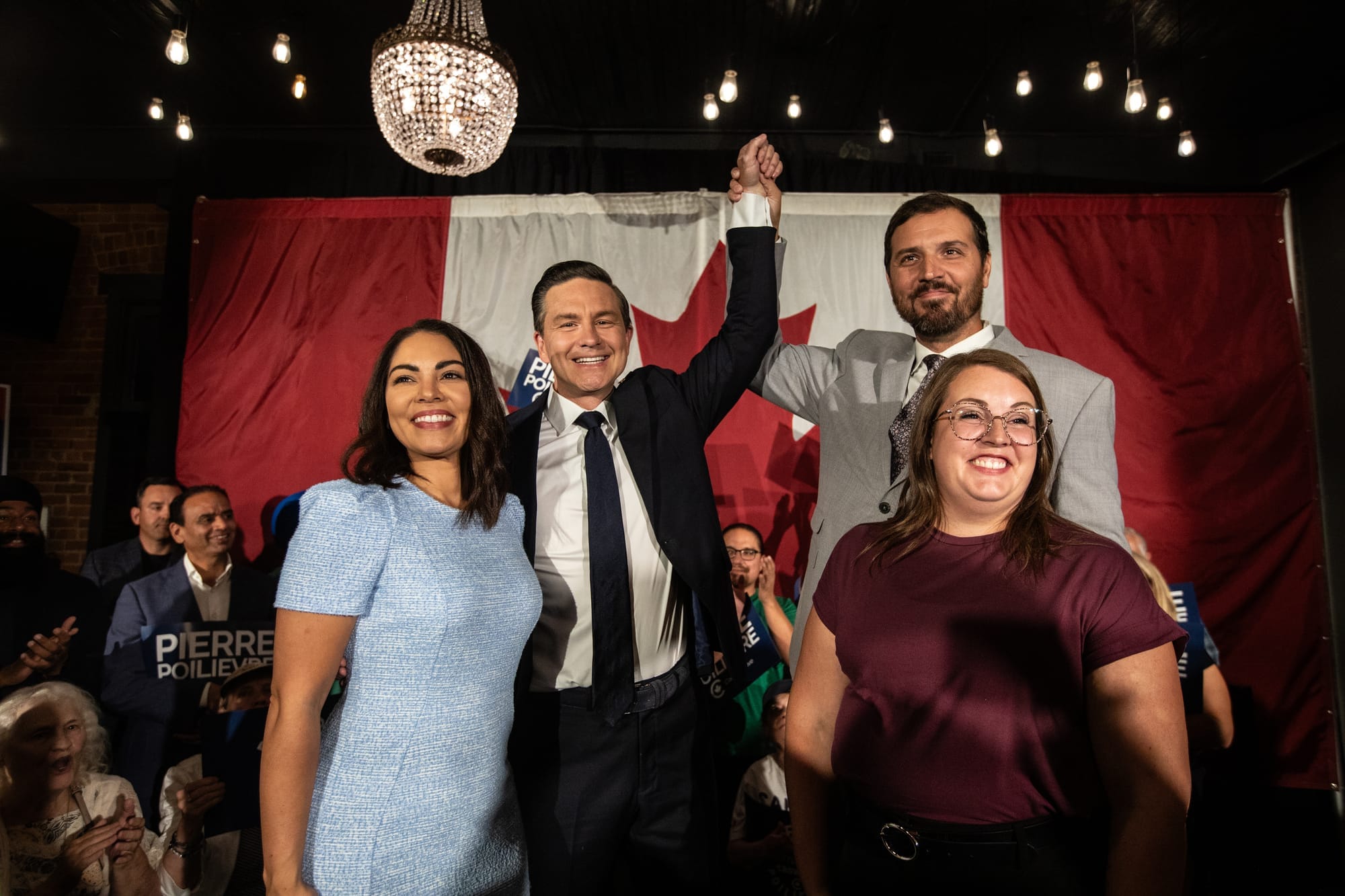 Pierre Poilievre and Damien Kurek smile in front of a Canadian flag as they celebrate Poilievre's by-election victory on Aug. 18.