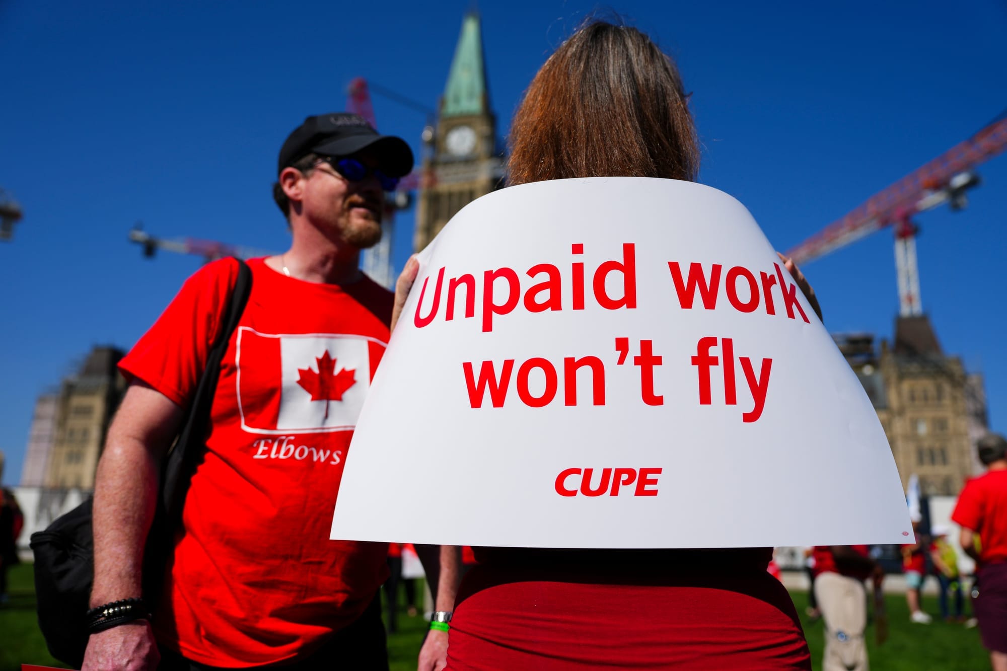 Flight attendants and supporters attend a rally for Air Canada flight attendants on Parliament Hill in September. One protestor carries the CUPE sign "Unpaid work won't fly."