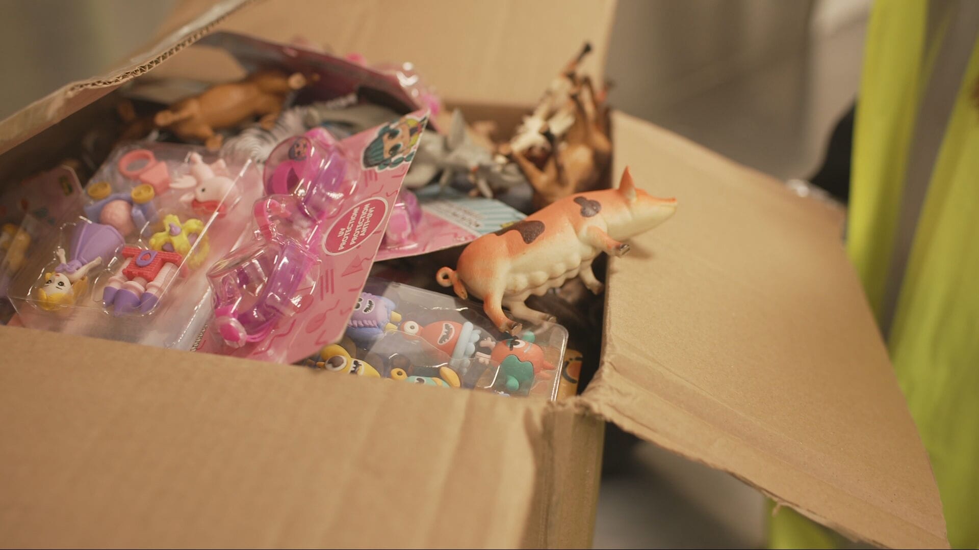 A cardboard box containing plastic children's toys. 