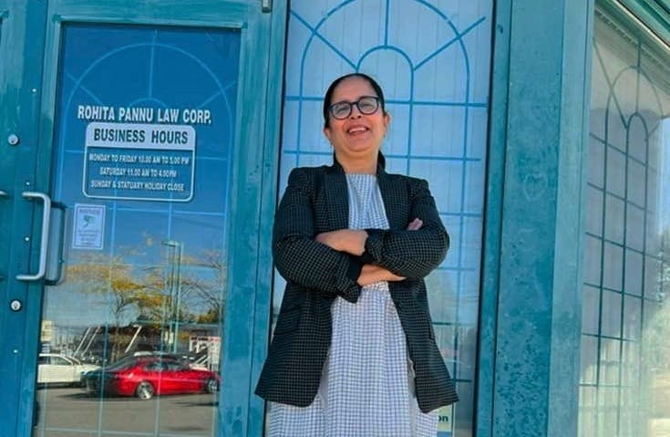 Lawyer Rohita Pannu stands with her arms crossed in front of an office with a sign reading 'Rohita Pannu Law Corp.'